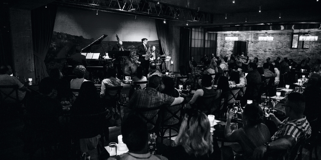 Audience captivated as they attentively watch jazz musicians perform on stage at Jazz, Tx